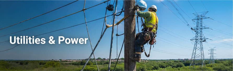 Lineman climbing a power pole with high-voltage transmission tower in the distance